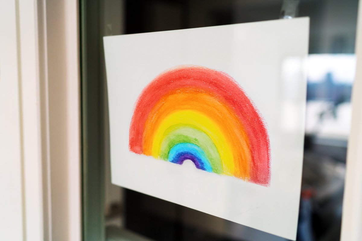 Barnetegning som forestiller en regnbue og henger på et vindu.
