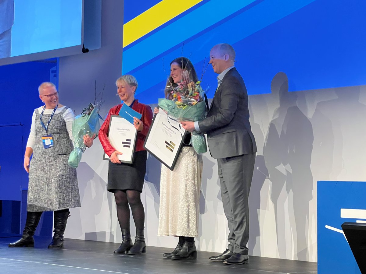 gruppe mennesker tar i mot diplom og blomster