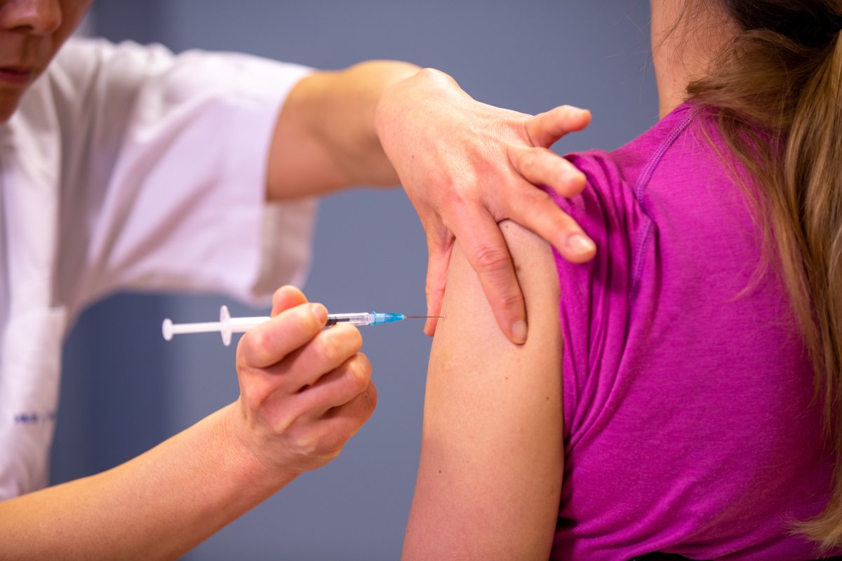 Helsepersonell setter influensavaksine på en privatperson.