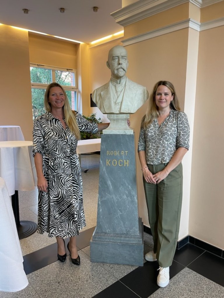 Bilde av Irene Olaussen og Pernille V. Dehli foran bysten av Robert Koch.