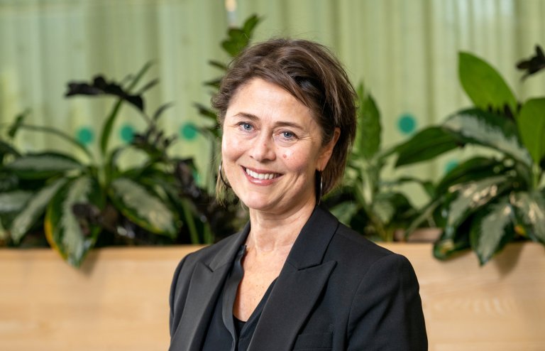 Smilende dame med kort mørkt hår og dressjakke