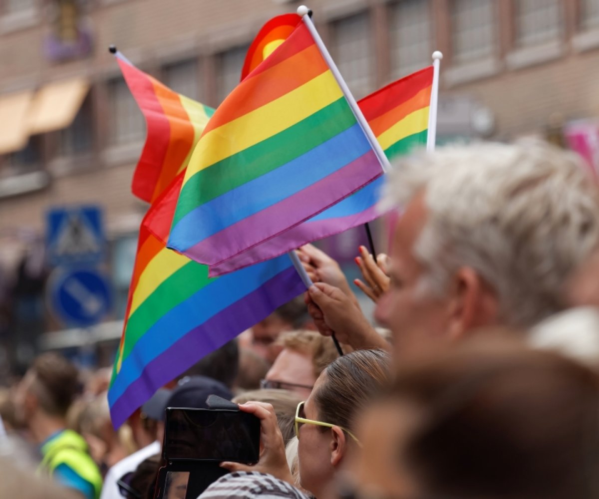 Folk som holder regnbueflagg i menneskemengde
