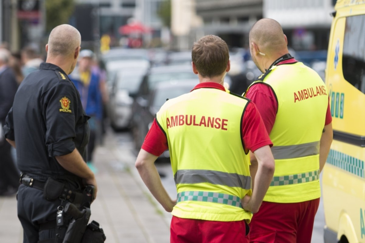 Bilde av politimann og to ambulansearbeidere i en bygate.