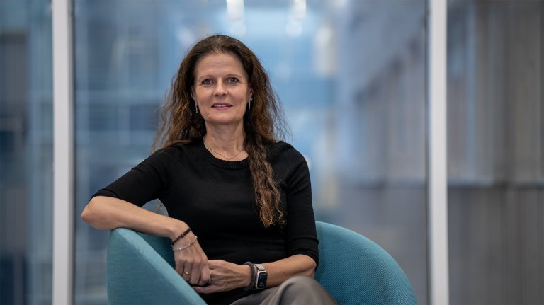 Smilende kvinne med langt hår sitter i stol